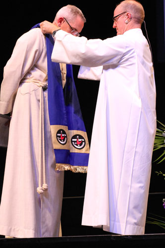 Outgoing President Rev Alistair Macrae passes the stole to new President Rev Prof Andrew Dutney during the installation service at the Adelaide Entertainment Centre, Sunday 15 July 2012 