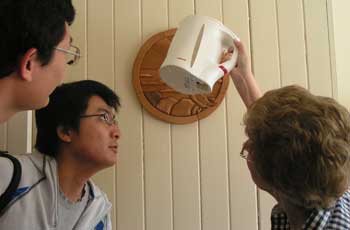 QUT engineering management students Lei Liu, and Chien-Ming examine energy consumption with Rev Heather Griffin at Sherwood Uniting Church
