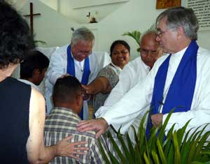 Judy Hunter Robinson, Apichart Branjerdporn, Vera Daitau, Iuma Apelu, and Bruce Johnson lay hands on Tupouniua Tauelangi during the confirmation service. Photos by Gwenda Brandjeporn