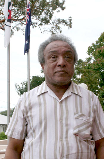 Ephrem Dehne Wold-Mariam stands proudly by the Australian and Uniting Church flags. After 16 years he is now a permanent Australian resident