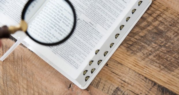 Photo of a magnifying glass over an open Bible.